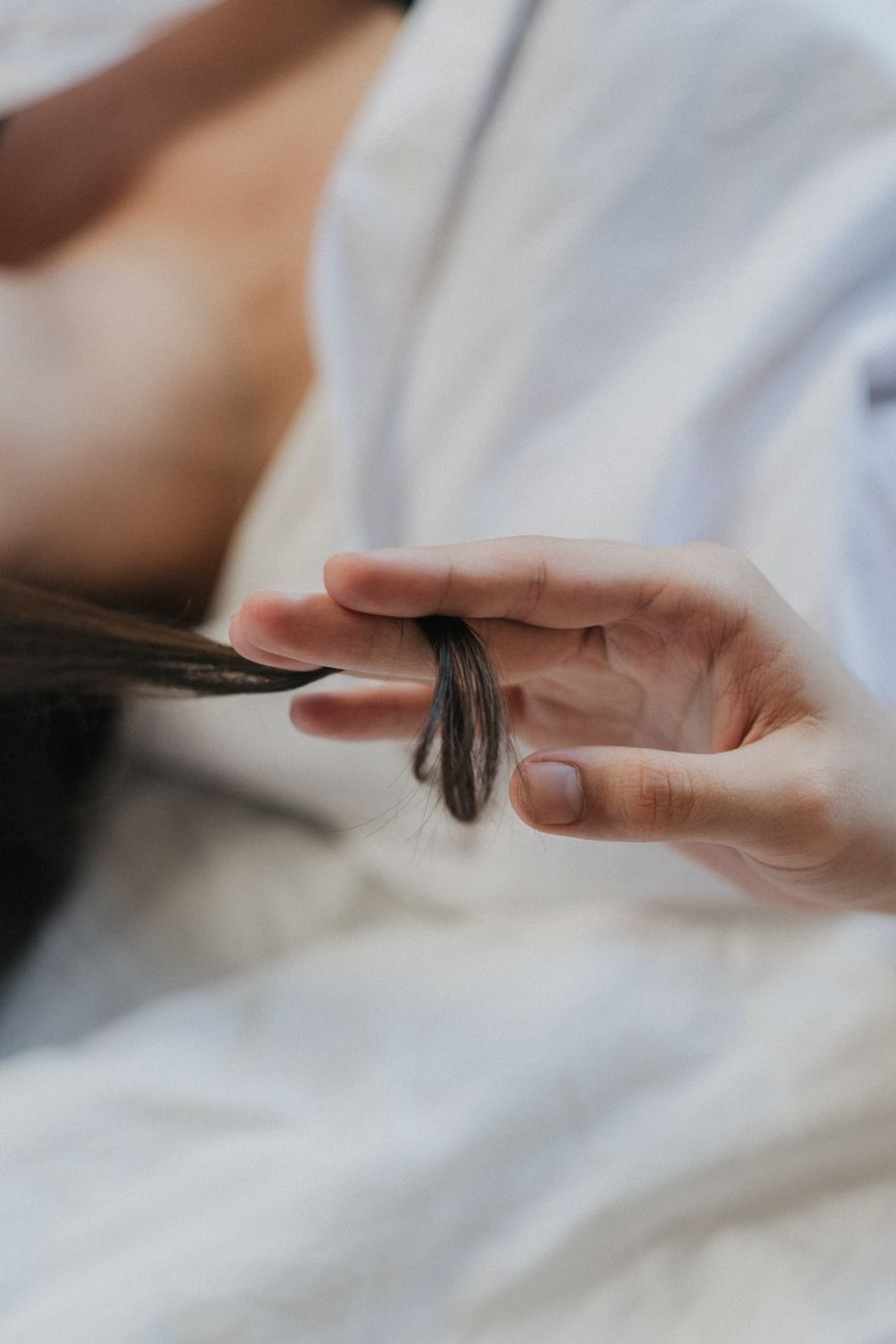 a person holding a lock of hair in between the fingers